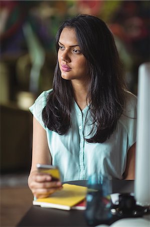 simsearch:6109-08701412,k - Businesswoman using mobile phone in office Stock Photo - Premium Royalty-Free, Code: 6109-08805169