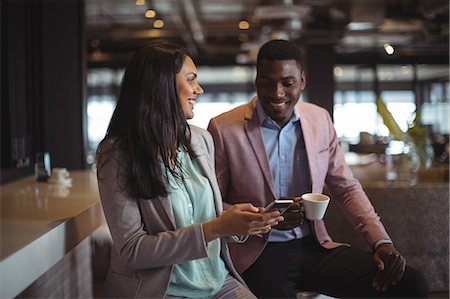 simsearch:6109-08805110,k - Businessman and a colleague discussing over mobile phone in office Photographie de stock - Premium Libres de Droits, Code: 6109-08805184