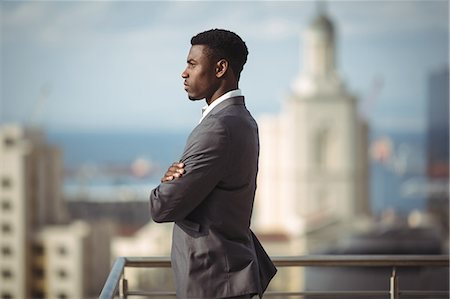 simsearch:6109-08805120,k - Side view of businessman standing with arms crossed on office terrace Stock Photo - Premium Royalty-Free, Code: 6109-08805120