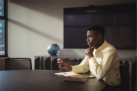 simsearch:6109-08489756,k - Businessman using mobile phone in office Stock Photo - Premium Royalty-Free, Code: 6109-08805127