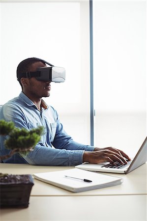 simsearch:6109-08701397,k - Business executive using virtual reality headset and working on laptop Stock Photo - Premium Royalty-Free, Code: 6109-08829635