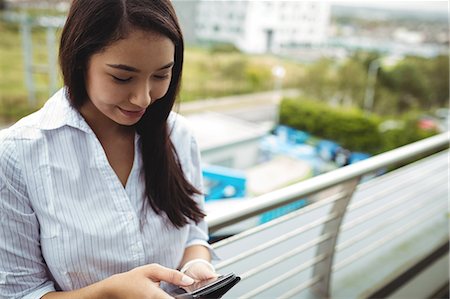 simsearch:6109-08829709,k - Businesswoman using mobile phone at office balcony Stock Photo - Premium Royalty-Free, Code: 6109-08829708