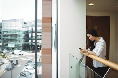 simsearch:6109-08829709,k - Businesswoman using mobile phone at office balcony Stock Photo - Premium Royalty-Free, Code: 6109-08829714