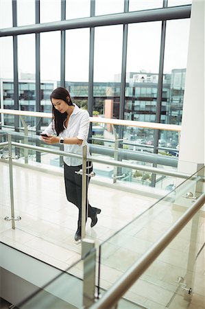 simsearch:6109-08829578,k - Businesswoman leaning on railing and using mobile phone Stock Photo - Premium Royalty-Free, Code: 6109-08829720