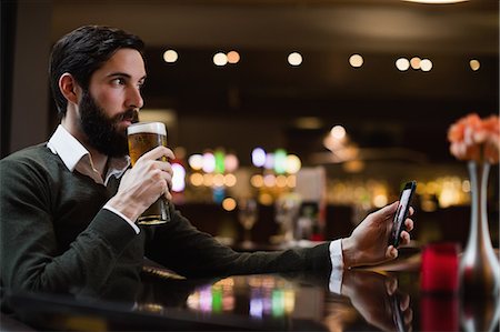 simsearch:6109-08944487,k - Man holding mobile phone and having glass of beer Photographie de stock - Premium Libres de Droits, Code: 6109-08829877