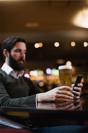 simsearch:6109-08782736,k - Man looking at mobile phone while having glass of beer Stock Photo - Premium Royalty-Free, Code: 6109-08829878