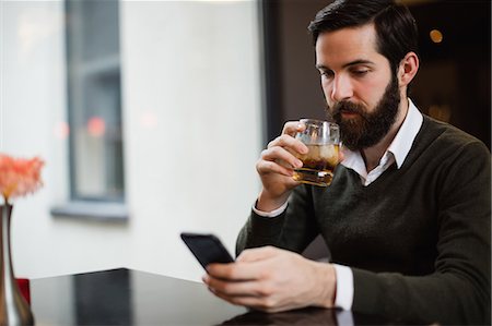 simsearch:6109-08782736,k - Man having glass of drink while using mobile phone Stock Photo - Premium Royalty-Free, Code: 6109-08829881