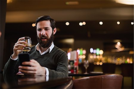 simsearch:6109-07600968,k - Man having glass of drink while using mobile phone Stock Photo - Premium Royalty-Free, Code: 6109-08829882
