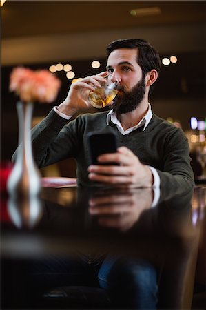 simsearch:6109-08782736,k - Man holding mobile phone and having a drink Stock Photo - Premium Royalty-Free, Code: 6109-08829885