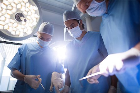 simsearch:6109-08829999,k - Group of surgeons performing operation in operation room Foto de stock - Sin royalties Premium, Código: 6109-08829997