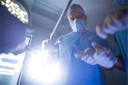 simsearch:6109-08389797,k - Surgeons performing operation in operation room Stock Photo - Premium Royalty-Free, Code: 6109-08829994