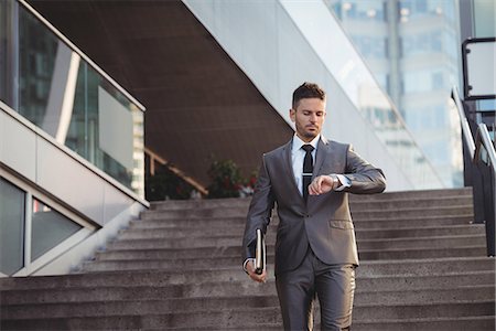 simsearch:6109-08805120,k - Businessman checking time while walking down stairs Stock Photo - Premium Royalty-Free, Code: 6109-08830053