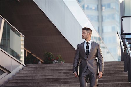 Businessman with a diary walking down stairs Stock Photo - Premium Royalty-Free, Code: 6109-08830052