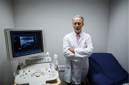 Surgeon with arms crossed standing near ultrasonic device machine Stock Photo - Premium Royalty-Free, Code: 6109-08830012