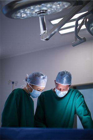 simsearch:6109-08830140,k - Surgeons performing operation in operation theater Foto de stock - Sin royalties Premium, Código: 6109-08830144