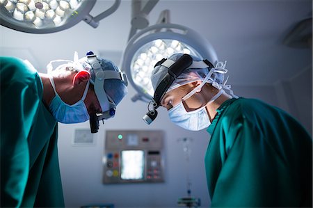 simsearch:6109-08689539,k - Surgeons wearing surgical loupes while performing operation Stock Photo - Premium Royalty-Free, Code: 6109-08830150