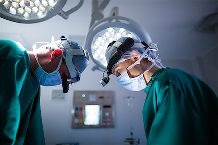 simsearch:6109-08830024,k - Surgeons wearing surgical loupes while performing operation Foto de stock - Sin royalties Premium, Código: 6109-08830150