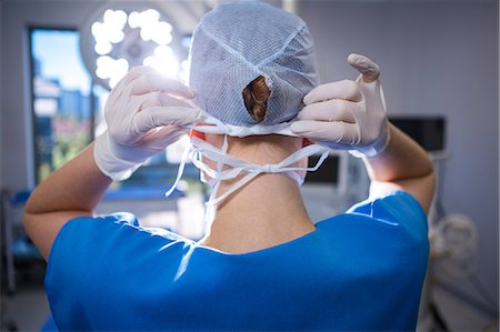 surgical glove - Rear view of female nurse wearing surgical cap in operation theater Photographie de stock - Premium Libres de Droits, Code: 6109-08830163