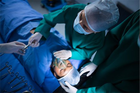 Surgeons performing operation in operation theater Foto de stock - Sin royalties Premium, Código: 6109-08830118
