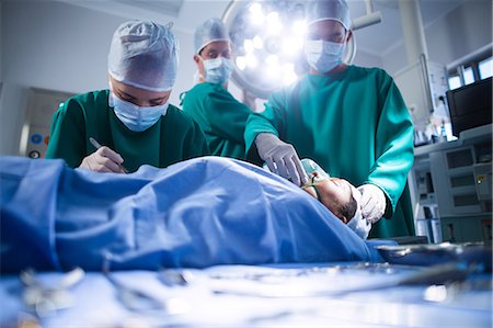 doctor with ethnic patient in office - Surgeons performing operation in operation theater Stock Photo - Premium Royalty-Free, Code: 6109-08830125