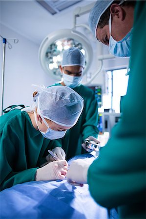 simsearch:6109-08830572,k - Surgeons performing operation in operation theater Photographie de stock - Premium Libres de Droits, Code: 6109-08830137