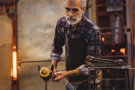 simsearch:6109-08830327,k - Glassblower shaping a molten glass Foto de stock - Royalty Free Premium, Número: 6109-08830307