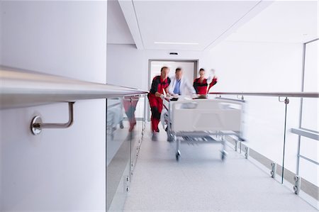 Doctors pushing emergency stretcher bed in corridor Fotografie stock - Premium Royalty-Free, Codice: 6109-08830403