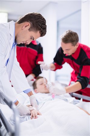 Doctors adjusting oxygen mask while rushing the patient in emergency room Foto de stock - Sin royalties Premium, Código: 6109-08830401