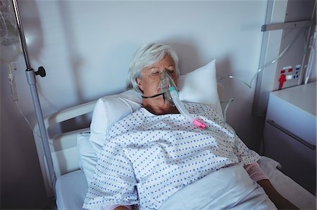 récupérer - Senior patient lying on bed with oxygen mask on face Foto de stock - Sin royalties Premium, Código: 6109-08830542