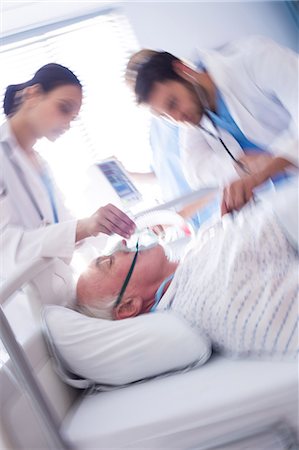 simsearch:6109-08830569,k - Team of doctors putting oxygen mask on patient face Photographie de stock - Premium Libres de Droits, Code: 6109-08830556