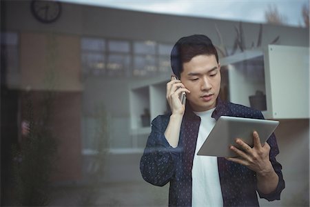 simsearch:6109-08782991,k - Business executive talking on mobile phone while using digital tablet Stock Photo - Premium Royalty-Free, Code: 6109-08830762