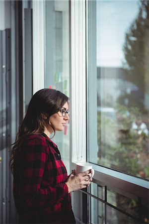 simsearch:6102-08329634,k - Thoughtful woman looking through window while having coffee Photographie de stock - Premium Libres de Droits, Code: 6109-08830730