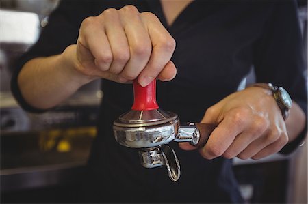 simsearch:6109-08203831,k - Close-up of waitress using a tamper to press ground coffee into a portafilter in cafe Stock Photo - Premium Royalty-Free, Code: 6109-08944142
