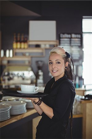 simsearch:6109-08944150,k - Portrait of waitress standing with cup of coffee in cafe Foto de stock - Royalty Free Premium, Número: 6109-08944152