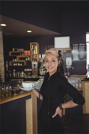 simsearch:6109-08829857,k - Portrait of waitress standing with cup of coffee in cafe Foto de stock - Royalty Free Premium, Número: 6109-08944155