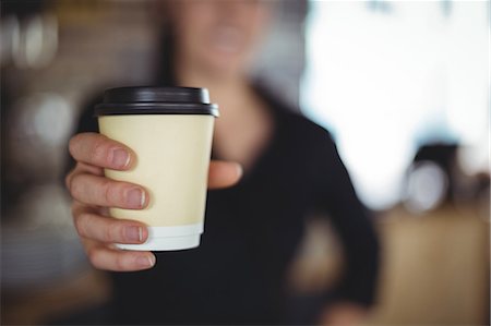 simsearch:6126-09104476,k - Close-up of waitress standing with disposable coffee cup in café Stock Photo - Premium Royalty-Free, Code: 6109-08944159
