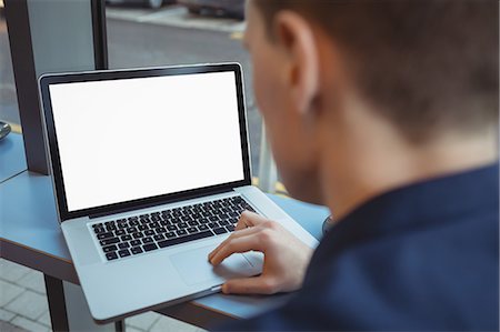 Male executive using laptop at counter in cafeteria Photographie de stock - Premium Libres de Droits, Code: 6109-08944262