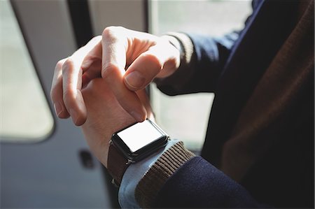 Mid-section of businessman using smartwatch while travelling in train Stock Photo - Premium Royalty-Free, Code: 6109-08944215