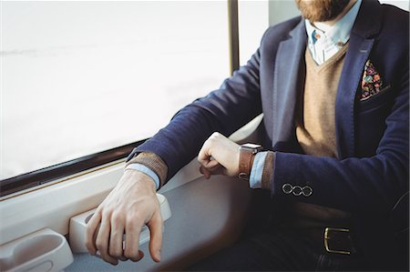 Mid-section of businessman checking time on smartwatch while travelling in train Stock Photo - Premium Royalty-Free, Code: 6109-08944223