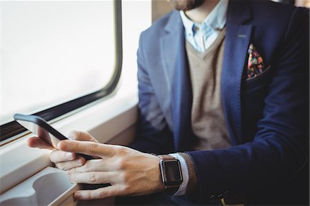 Mid-section of businessman using mobile phone while travelling in train Stock Photo - Premium Royalty-Free, Code: 6109-08944225