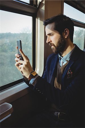 Businessman taking picture from mobile phone while travelling in train Stock Photo - Premium Royalty-Free, Code: 6109-08944226