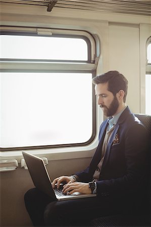 Businessman using laptop while travelling in train Stock Photo - Premium Royalty-Free, Code: 6109-08944229