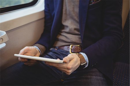 Mid-section of businessman holding digital tablet while travelling in train Stock Photo - Premium Royalty-Free, Code: 6109-08944232