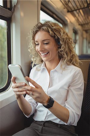 simsearch:6109-08944310,k - Smiling woman using mobile phone inside train compartment Photographie de stock - Premium Libres de Droits, Code: 6109-08944328