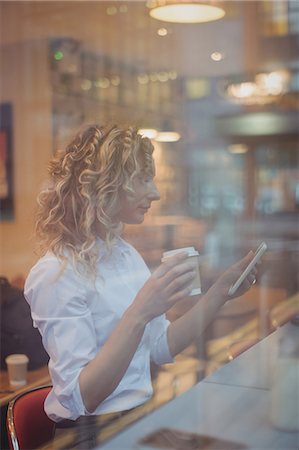 simsearch:6109-08944310,k - Woman using mobile phone while having coffee at counter in cafeteria Photographie de stock - Premium Libres de Droits, Code: 6109-08944335
