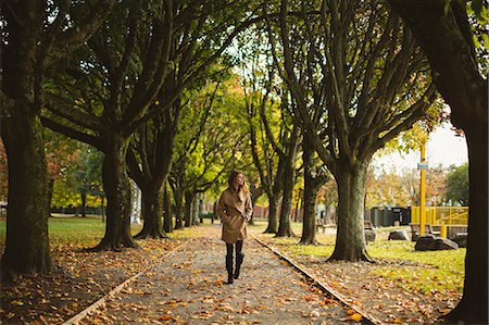 simsearch:6109-08944840,k - Woman with hands in her pocket walking in the park Fotografie stock - Premium Royalty-Free, Codice: 6109-08944440