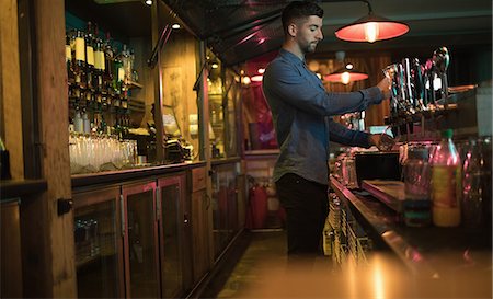 Bartender filling beer from bar pump at bar counter Stock Photo - Premium Royalty-Free, Code: 6109-08944453