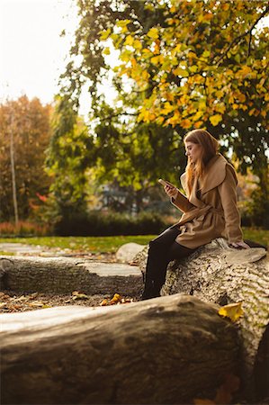 simsearch:6109-08944833,k - Woman using mobile phone while sitting on a tree trunk in park Photographie de stock - Premium Libres de Droits, Code: 6109-08944450