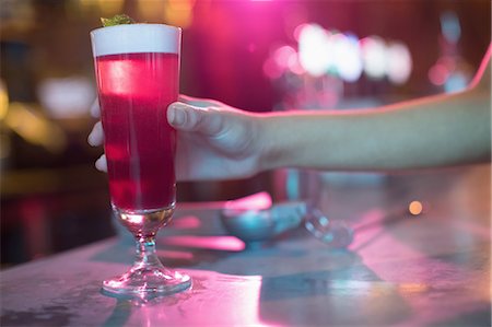 store juice - Woman holding a glass of pink cocktail in bar Stock Photo - Premium Royalty-Free, Code: 6109-08944471