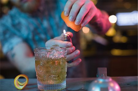 simsearch:6109-08945043,k - Bartender preparing a flaming cocktail at counter in bar Foto de stock - Sin royalties Premium, Código: 6109-08944480